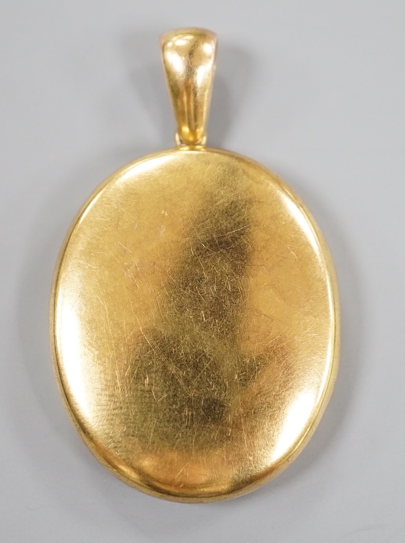 A late Victorian yellow metal oval mourning locket, containing plaited hair, overall 50mm, gross weight 14.7 grams.